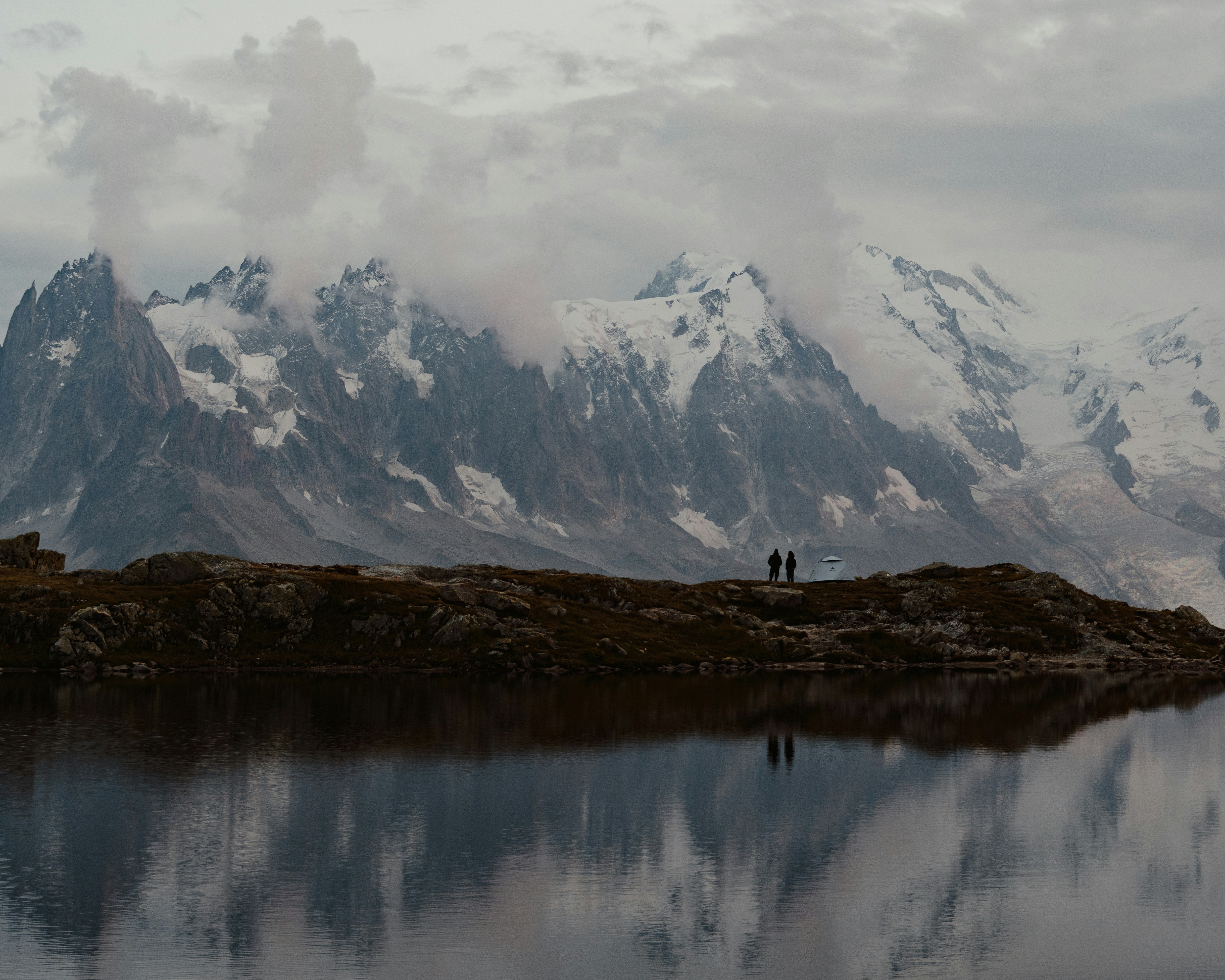 snow covered mountain near lake during daytime